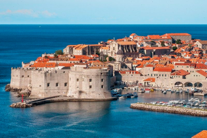 a large ship in a body of water with Dubrovnik in the background